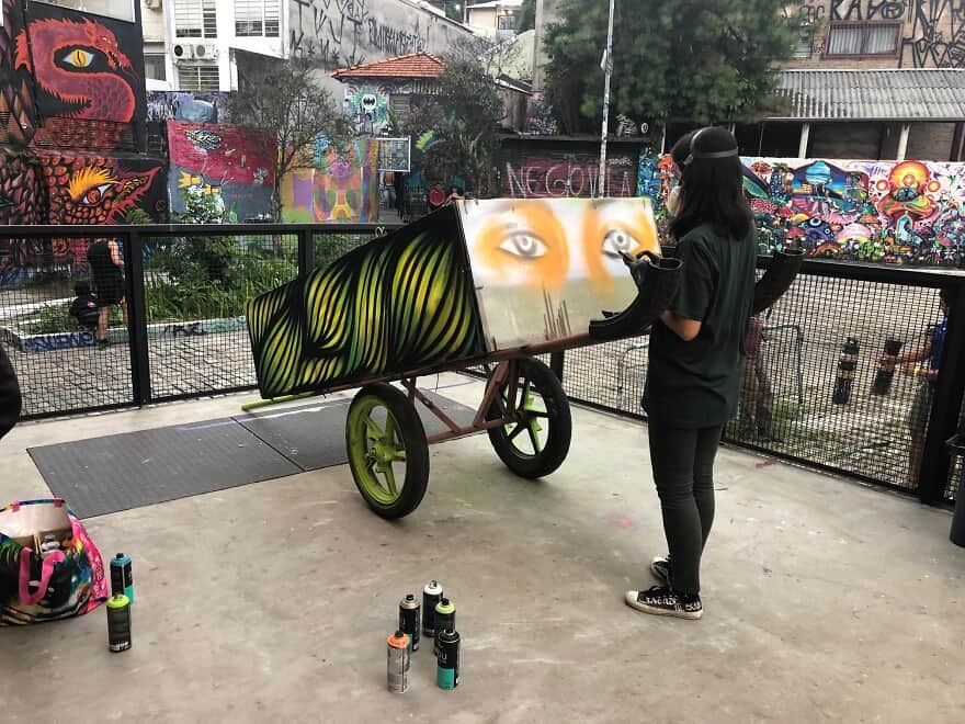 Artista grafitando uma carroça de reciclagem da 